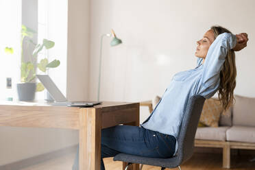 Entspannte Unternehmerin mit geschlossenen Augen, die zu Hause vor ihrem Laptop sitzt - SBOF03405