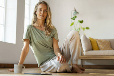 Woman with blond hair sitting on floor at home - SBOF03485