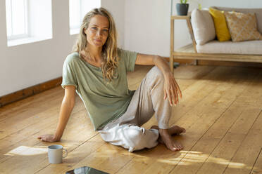 Relaxed woman sitting on floor in living room - SBOF03486