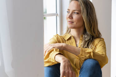 Woman day dreaming while sitting at window - SBOF03495