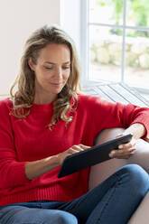 Beautiful woman using digital tablet at home - SBOF03518