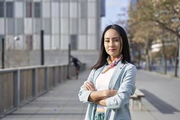 Businesswoman standing with arms crossed on footpath - VEGF04122