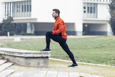 Determined male athlete doing stretching exercise at park - JSRF01461