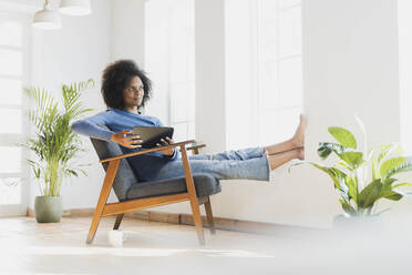 Nachdenkliche Frau mit digitalem Tablet, die zu Hause sitzt - SBOF03545
