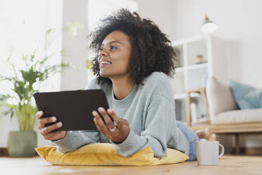 Junge Frau mit digitalem Tablet, das zu Hause auf dem Boden liegt - SBOF03558