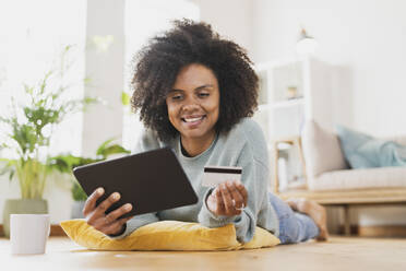 Young smiling woman with digital tablet and credit card at home - SBOF03559