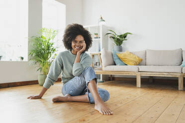 Smiling woman sitting on floor at home - SBOF03561