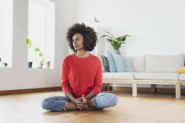 Young woman sitting with cross-legged on floor at home - SBOF03562