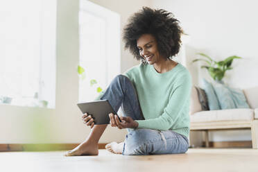 Young woman smiling while using digital tablet at home - SBOF03565