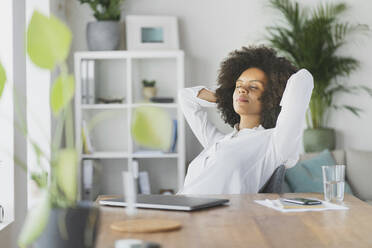 Woman relaxing with hands behind head at home - SBOF03581