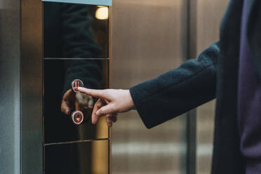 Businessman touching lift button at hotel - DGOF02037