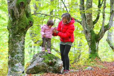 Mutter hält die Hand ihrer Tochter, die auf einem Felsen im Naturpark Gorbea steht - DSGF02386