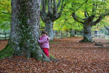 Mädchen lehnt an einem Baumstamm im Naturpark Gorbea - DSGF02396