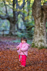 Mädchen steht auf Herbstblättern im Naturpark Gorbea - DSGF02397