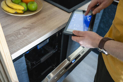 Man operating oven through digital tablet in kitchen - VPIF03884
