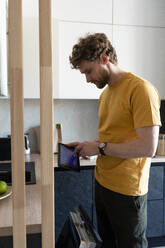 Man using digital tablet in kitchen at home - VPIF03886