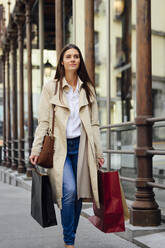 Woman walking on footpath while shopping in city - PGF00493