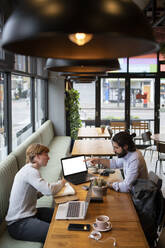 Männliche Unternehmer diskutieren am Laptop im Coworking-Büro - FBAF01696