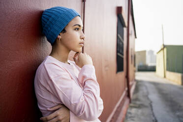 Contemplating woman with hand on chin standing in front of wall - RCPF00934