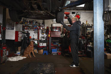 Ein älterer männlicher Mechaniker ersetzt einen Reifen in einer Werkstatt - PMF01739