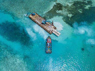 Luftaufnahme von Erdbewegungsmaschinen, die Masten auf einer schwimmenden Plattform im Male-Atoll transportieren - KNTF06194