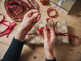 Frau hält Schaukelpferd Spielzeug über Geschenk auf dem Tisch während Weihnachten - PWF00269