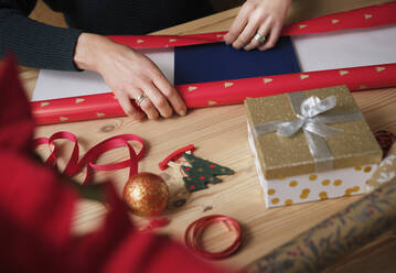 Woman wrapping gift by during Christmas on table - PWF00270