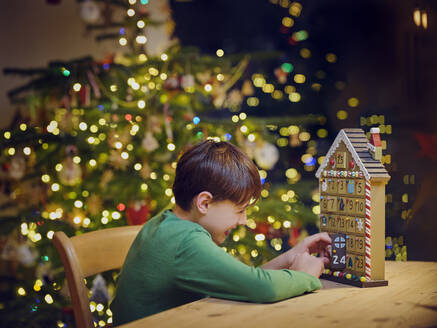 Playful boy opening advent calender door during Christmas at home - PWF00277