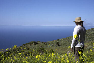 Männlicher Wanderer mit Blick auf das Meer an einem sonnigen Tag - PSTF00903