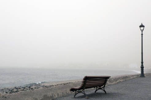 Bench and street light by seashore in front of clear sky - PSTF00907