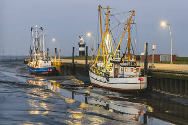 Germany, Lower Saxony, Wurster Nordseekuste, Fishing boats moored in beachside harbor at dusk - KEBF01846