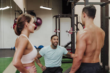 Sportler lächelt, während er seine Freunde im Fitnessstudio anschaut - EBBF02862