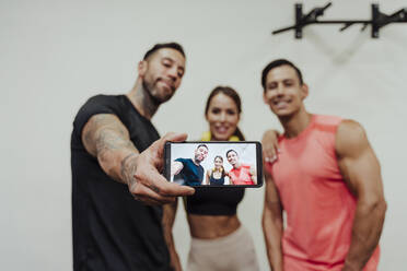 Mittlerer Erwachsener, der ein Selfie mit seinem Handy im Fitnessstudio macht - EBBF02882