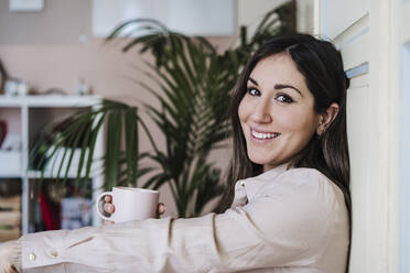 Happy beautiful woman holding coffee cup at home - EBBF02913