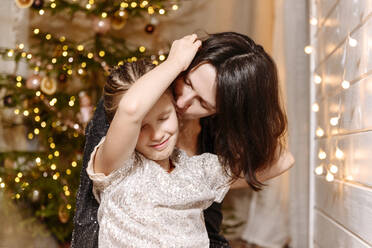 Mutter küsst Tochter zu Hause während Weihnachten - EYAF01559