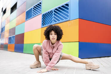 Female dancer dancing while crouching on footpath - JCCMF01578