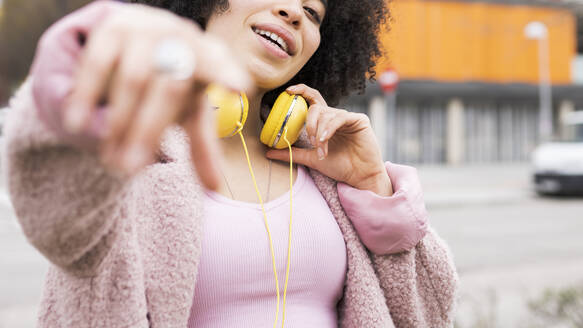 Young woman with jacket and headphones gesturing while singing - JCCMF01590