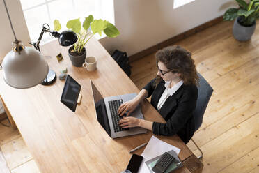 Businesswoman using laptop at home office - SBOF03608