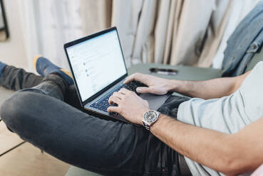 Mittlerer erwachsener Mann, der im Hotel sitzend einen Laptop benutzt - DGOF02050