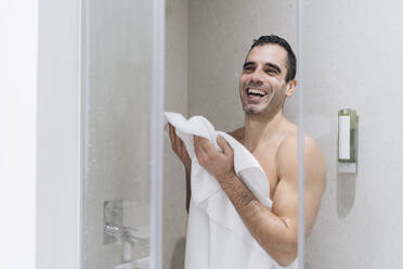 Gut gelaunter Mann, der sich nach einem Bad mit einem Handtuch abtrocknet - DGOF02077