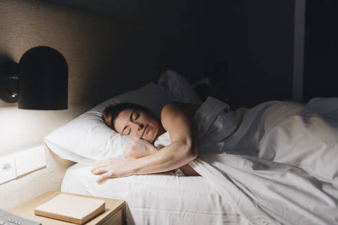 Schöne Frau schläft auf dem Bett im Hotelzimmer - DGOF02092