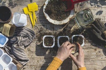 Mid adult woman putting seeds in container on table during springime at garden - SKCF00732