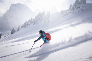 Mittlere erwachsene Frau beim Skifahren auf einem schneebedeckten Berg an einem sonnigen Tag - MALF00345