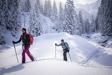 Mittlere erwachsene Frau beim Skitourengehen mit Mann an einem sonnigen Tag - MALF00349