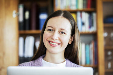 Smiling female student looking away at home - SGF02800