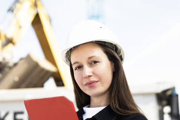 Ingenieurin mit Schutzhelm und Klemmbrett auf der Baustelle - SGF02806