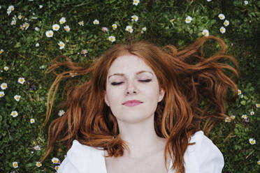 Young redhead woman lying on grass - EBBF02925