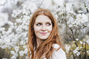 Smiling young redhead woman with gray eyes looking away - EBBF02948