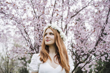 Beautiful woman wearing white flower tiara looking away - EBBF02963