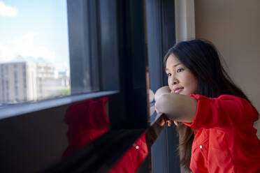 Thoughtful young woman looking through window - BMOF00517